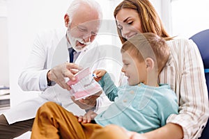 Dentist educating child patient about teeth brushing techniques