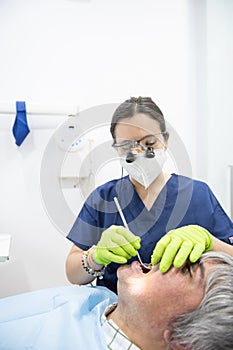 Dentist  in exam room with mature patient man in chair