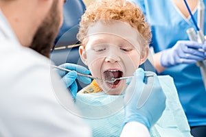 Dentist examinating boy`s teeth
