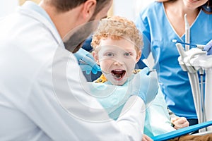 Dentist examinating boy`s teeth photo