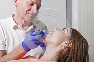 Dentist examines gums and teeth of his female patient