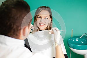 Dentist examines teeth of his patient. Attractive girl is being examined by a dentist