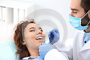 Dentist examining African-American woman`s teeth