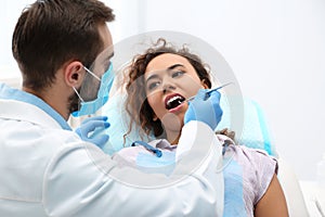 Dentist examining African-American woman`s teeth