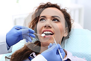 Dentist examining African-American woman`s teeth with probe and mirror