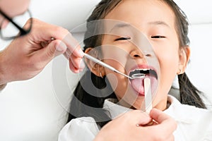 Dentist examining child teeth in dental clinic.