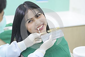 Dentist is examining female patient`s teeth by using the whitening level