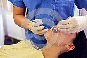 Dentist examining female`s teeth in a dentistry.
