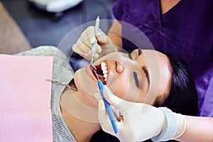 Dentist examining female`s teeth in dentistry.