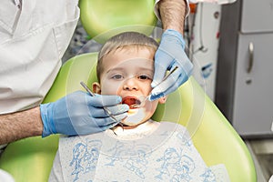 Dentist examining little boy`s teeth in clinic. Dental problem.