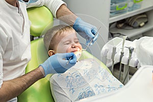 Dentist examining little boy`s teeth in clinic. Dental problem.