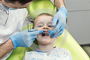 Dentist examining little boy`s teeth in clinic. Dental problem.