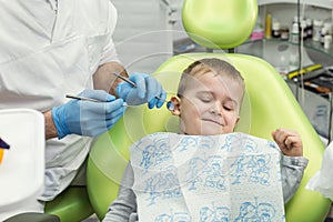 Dentist examining little boy`s teeth in clinic. Dental problem.