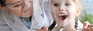 Dentist examining mouth of little girl with instruments