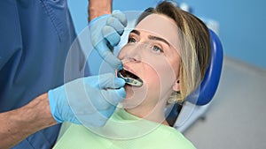 Dentist examining a patient`s teeth with dental equipment impression spoon in dentistry office. Stomatology and health