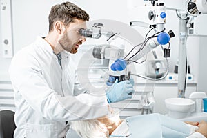 Dentist examining patient`s teeth with a microscope