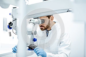 Dentist examining patient`s teeth with a microscope
