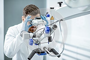 Dentist examining patient`s teeth with a microscope