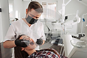 Dentist examining patient teeth with a mouth mirror and dental excavator. Close-up view on the woman`s face