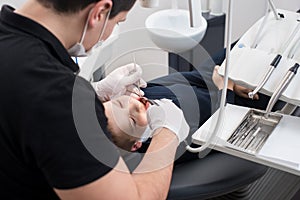 Dentist examining teeth of boy patient in dental clinic using dental tools