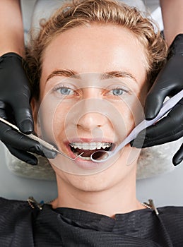 Dentist examining woman teeth with braces.