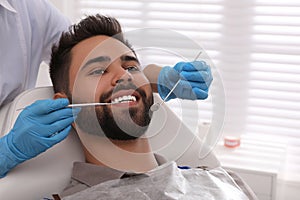 Dentist examining young man`s teeth in modern clinic