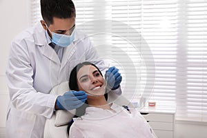Dentist examining young woman`s teeth in modern clinic
