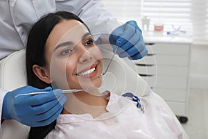 Dentist examining young woman`s teeth in modern clinic