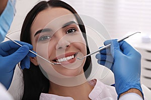 Dentist examining young woman`s teeth in modern clinic