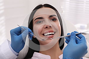 Dentist examining young woman`s teeth in modern clinic