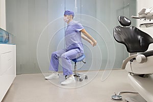 Dentist exercising on mobile dental saddle in his office