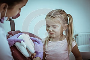 Dentist explain little girl teeth hygiene.