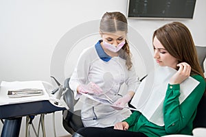 Dentist explaining the details of x-ray image to patient in dental office and preparing for treatment. Dentistry