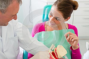 Dentist explaining teeth brushing to patient photo