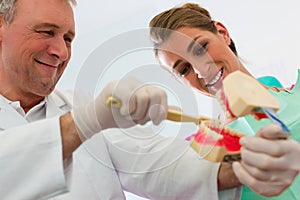 Dentist explaining teeth brushing to patient photo