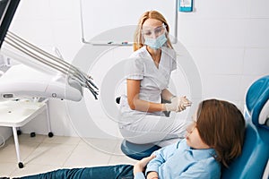 Dentist in face shield taking care of boy patient