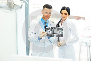 Dentist and female assistant are discussing dental X Ray image