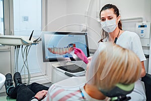 Dentist female doctor in uniform showing scan of intraoral 3D dental scanner Machine to patient. Dental clinic patient visit