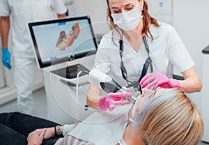 Dentist female doctor in uniform using intraoral 3D dental scanner Machine for clear aligners production. Dental clinic patient