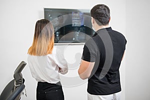 Dentist with female patient looking at dental x-ray image on computer screen