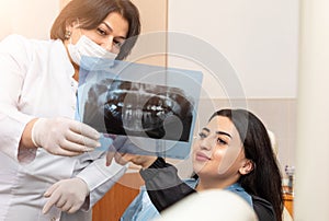 Dentist and female patient looking to x-ray