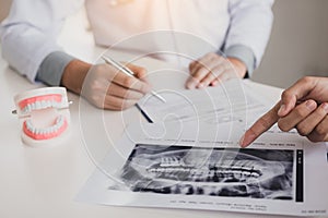 Dentist hand holding pen and talking to the patient with pointing x-ray picture about medication and surgery treatment