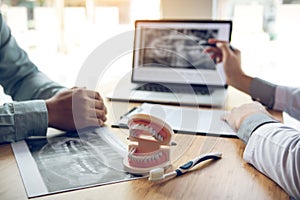 Dentist hand pointing x-ray picture in laptop computer and talking to the patient about medication and surgery treatment