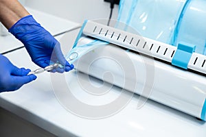 Dentist hands in blue gloves holding dentist tools using sterilizing box