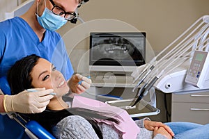 A dentist hands working on young woman patient with dental tools.