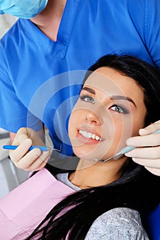 A dentist hands working on young woman patient with dental tools.