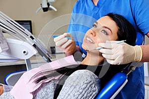 A dentist hands working on young woman patient with dental tools.