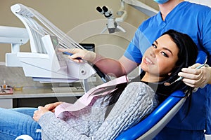 A dentist hands working on young woman patient with dental tools.