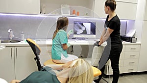 A dentist and her assistant talking about an x-ray of a patientÂ´s teeth