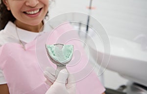 Dentist holding dental impressions on the background of a patient woman smiling toothy smile. Dental molds from upper jaw of